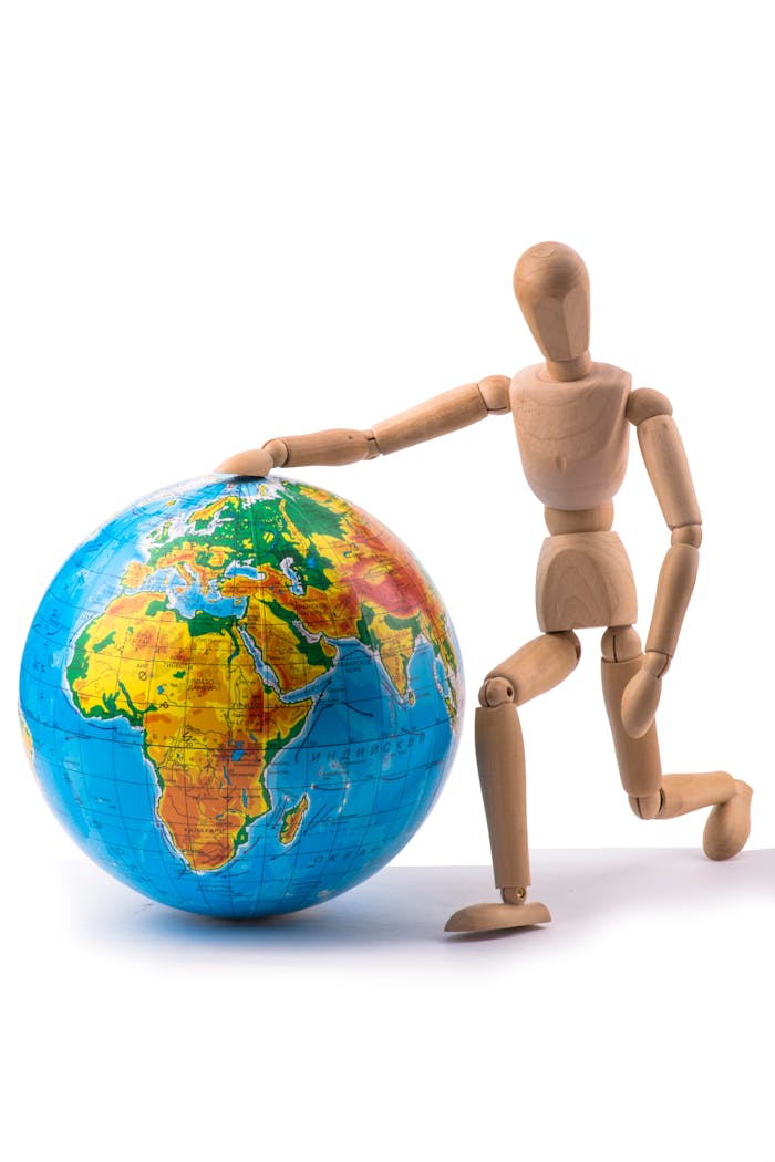 A wooden mannequin poses with a vibrant world globe, representing global unity.